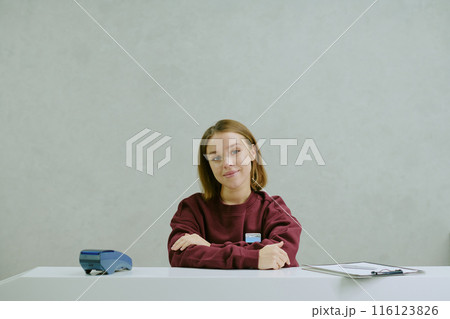 Young professional manager sitting at snow white work desk, she folding her arms and smiling lightly 116123826