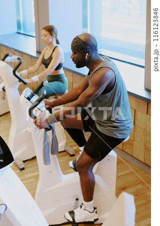 High angle shot of gym visitors warming up in cardio zone of premium fitness club, they doing cardio on exercise bike High angle shot of gym visitors warming up in cardio zone of premium fitness club, they doing cardio on exercise bike 116123846