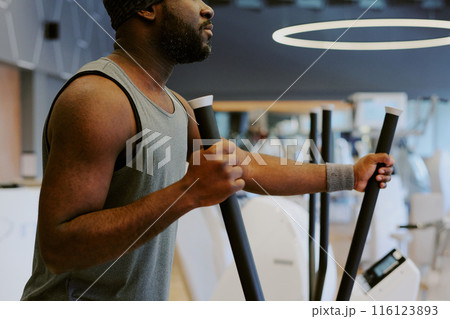 Medium close up of African American man doing cardio, he using elliptical machine 116123893
