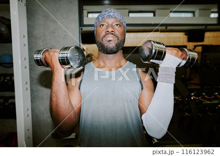 African American man lifting heavy dumbbells, he focused on exercise technique African American man lifting heavy dumbbells, he focused on exercise technique 116123962
