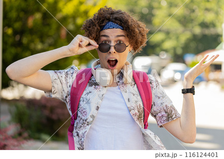 Happy man taking off sunglasses looking surprised at camera with big open eyes, shocked by victory 116124401