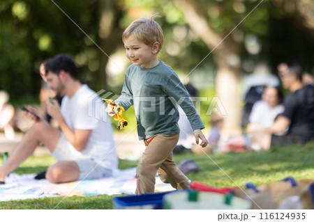 A young boy is playing with a toy truck in a park 116124935