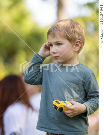 A young boy is holding a toy car and talking on a cell phone 116124941