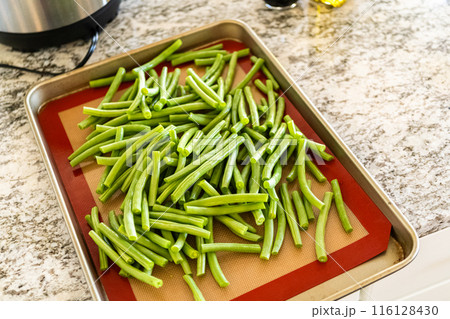 Watch as fresh green beans are beautifully roasted to perfection on a baking sheet with a silicone mat, adding a burst of flavor to your meal. Watch as fresh green beans are beautifully roasted to perfection on a baking sheet with a silicone mat, adding a burst of flavor to your meal. 116128430