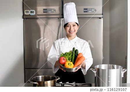 沢山の野菜を持つ若いアジア人の女性調理師 沢山の野菜を持つ若いアジア人の女性調理師 116129107