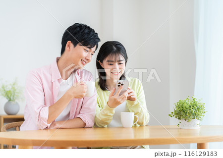 自宅でスマホを見る若いカップル 自宅でスマホを見る若いカップル 116129183