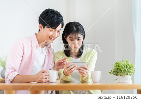 スマホで動画を見る若い夫婦 116129250