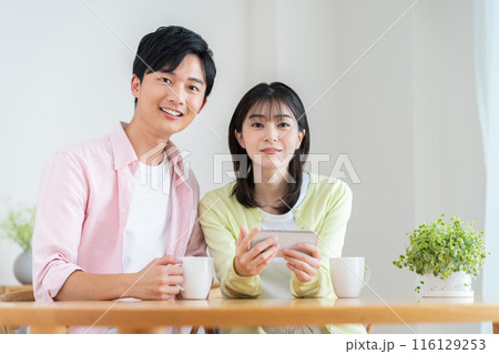 スマホで動画を見る若い夫婦 スマホで動画を見る若い夫婦 116129253