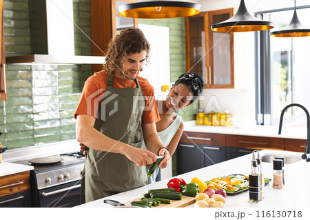 A diverse couple is preparing food together in modern kitchen 116130718