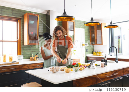 A diverse couple is preparing meal together in a modern kitchen A diverse couple is preparing meal together in a modern kitchen 116130719