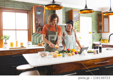 A diverse couple is preparing meal together in a modern kitchen 116130723