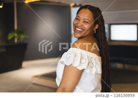 A young biracial woman is smiling in a modern business office with copy space 116130959