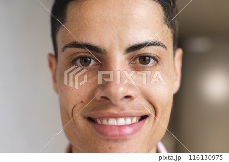 A young biracial man with short hair is smiling in a modern business office A young biracial man with short hair is smiling in a modern business office 116130975