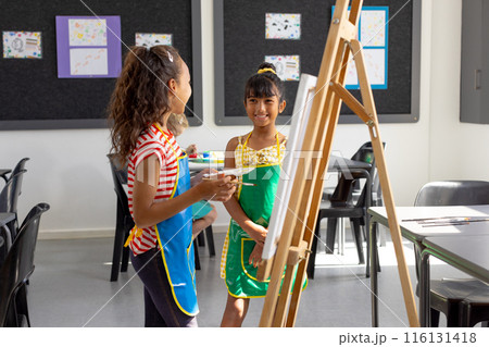 In school, in art class, biracial and a Caucasian girl, both young, are painting In school, in art class, biracial and a Caucasian girl, both young, are painting 116131418