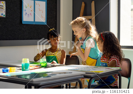 In school, three young girls are focusing on painting in art class In school, three young girls are focusing on painting in art class 116131421