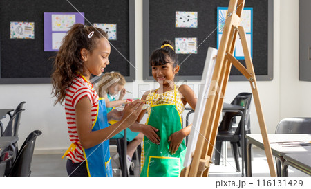 In school, in art class, a diverse group of young girls are painting 116131429