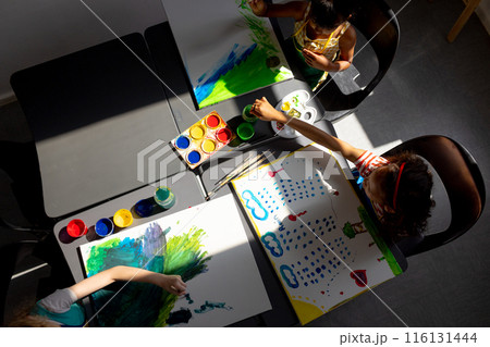 In school, in art class, biracial and a Caucasian girl, both young, are painting In school, in art class, biracial and a Caucasian girl, both young, are painting 116131444