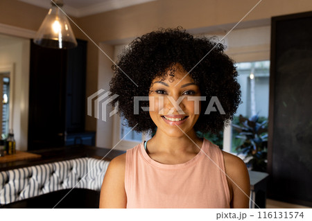Biracial young woman standing in kitchen, smiling at camera at home 116131574