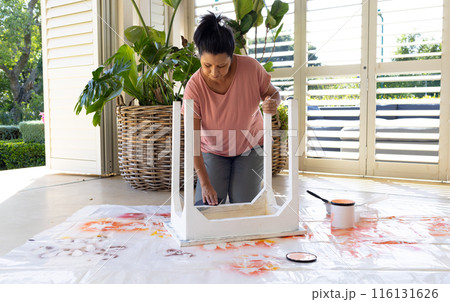 Mature biracial woman painting furniture at home in an upcycling project Mature biracial woman painting furniture at home in an upcycling project 116131626