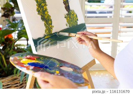 Biracial young woman is painting on canvas outdoors at home 116131670