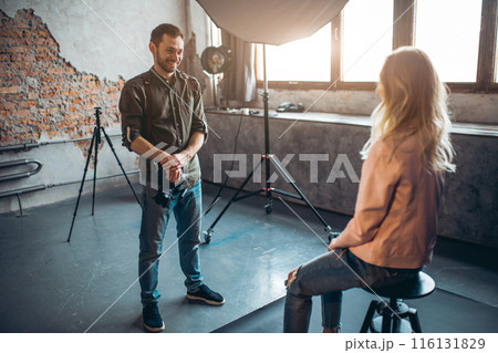 positive photographer telling jokes to a blond model after photo session positive photographer telling jokes to a blond model after photo session 116131829