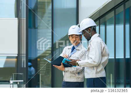 ビルの前で会話する多国籍エンジニアのグループ 116132365