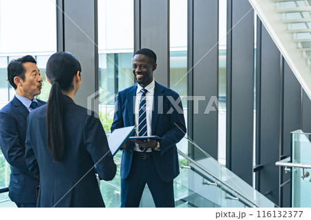 ロビーで会話する多国籍ビジネスパーソンのグループ 116132377