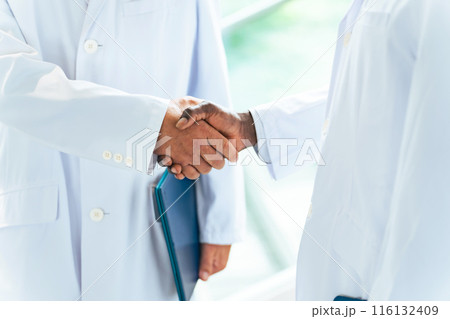 ロビーで握手する白衣の多国籍グループ 116132409