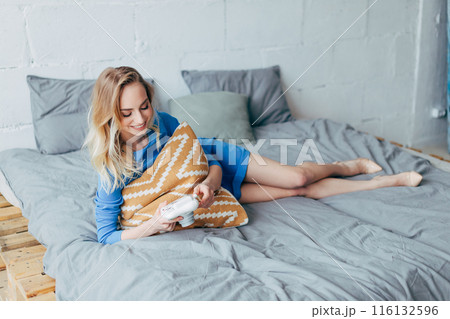 girl hugging the pillow and looking at the photos from the digital camera 116132596
