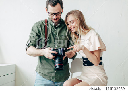 a pleasant photographer showing models the photos on his camera 116132689
