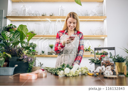 smiling lady florist with mobile phone at work smiling lady florist with mobile phone at work 116132843