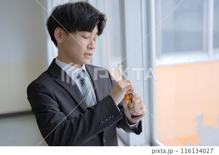 栄養ドリンクを開けるビジネスマン 116134027