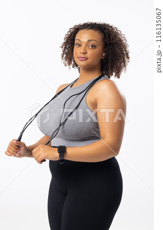 A biracial young female plus size model holding a jump rope on a white background 116135067