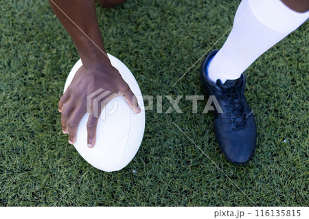 African American young male athlete model holding rugby ball on field outdoors on grass 116135815
