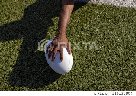 African American young male athlete holding a rugby ball on grass, copy space African American young male athlete holding a rugby ball on grass, copy space 116135904