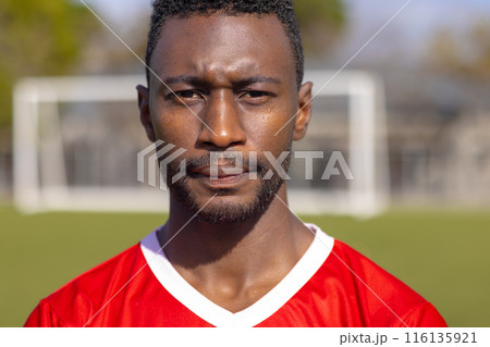 African American young male athlete standing on soccer field outdoors, looking serious, copy space 116135921