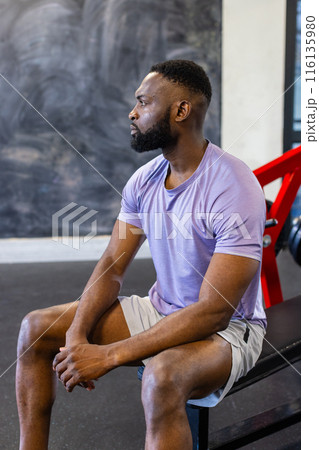 African American young male athlete sitting on a bench in a gym, resting, copy space 116135980