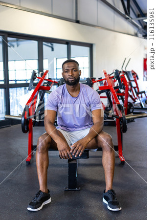 African American young male athlete and fitness model sitting in gym, looking at camera 116135981