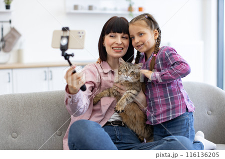 Mother and daughter taking selfie with cat at home 116136205