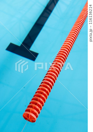 A red and white lane divider floats in an indoor blue swimming pool, copy space A red and white lane divider floats in an indoor blue swimming pool, copy space 116136214