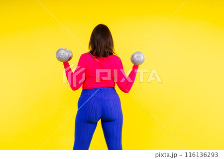 Sporty model with curvy figure with dumbbells. Dynamic movement. Motivation and healthy lifestyle Sporty model with curvy figure with dumbbells. Dynamic movement. Motivation and healthy lifestyle 116136293