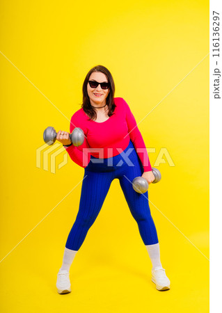 Sporty model with curvy figure with dumbbells. Dynamic movement. Motivation and healthy lifestyle 116136297