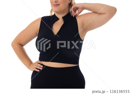 Caucasian plus-size young woman in black sportswear poses confidently on white bg 116136555