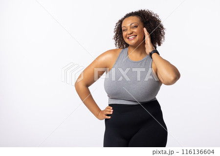 A biracial plus size model with curly hair laughs on white background, copy space A biracial plus size model with curly hair laughs on white background, copy space 116136604