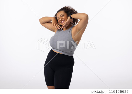 Biracial plus size young female model poses, hands on head, smiling, white background, copy space 116136625
