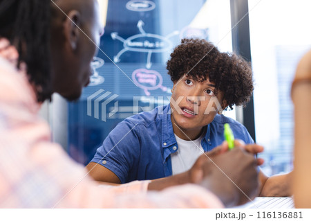 Diverse group of colleagues discussing, sitting around a table in a modern business office Diverse group of colleagues discussing, sitting around a table in a modern business office 116136881