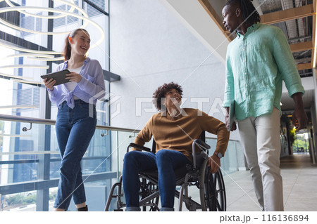 Diverse colleagues walking and talking in bright hallway in a modern business office 116136894