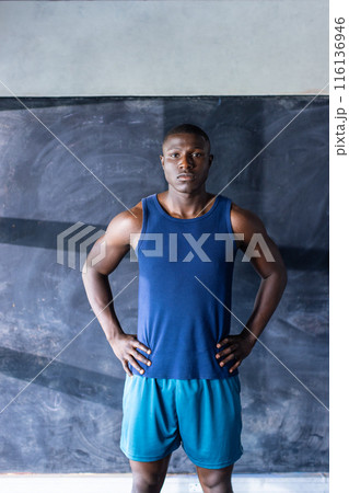 Confident African American athlete and fitness model stands in gym, hands on hips 116136946