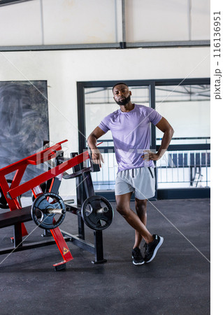 African American male athlete, fitness model, leans on gym equipment African American male athlete, fitness model, leans on gym equipment 116136951