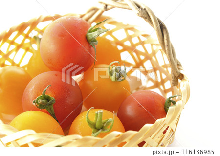竹かごに沢山入っている黄色と赤色のミニトマトを白背景で撮影 116136985